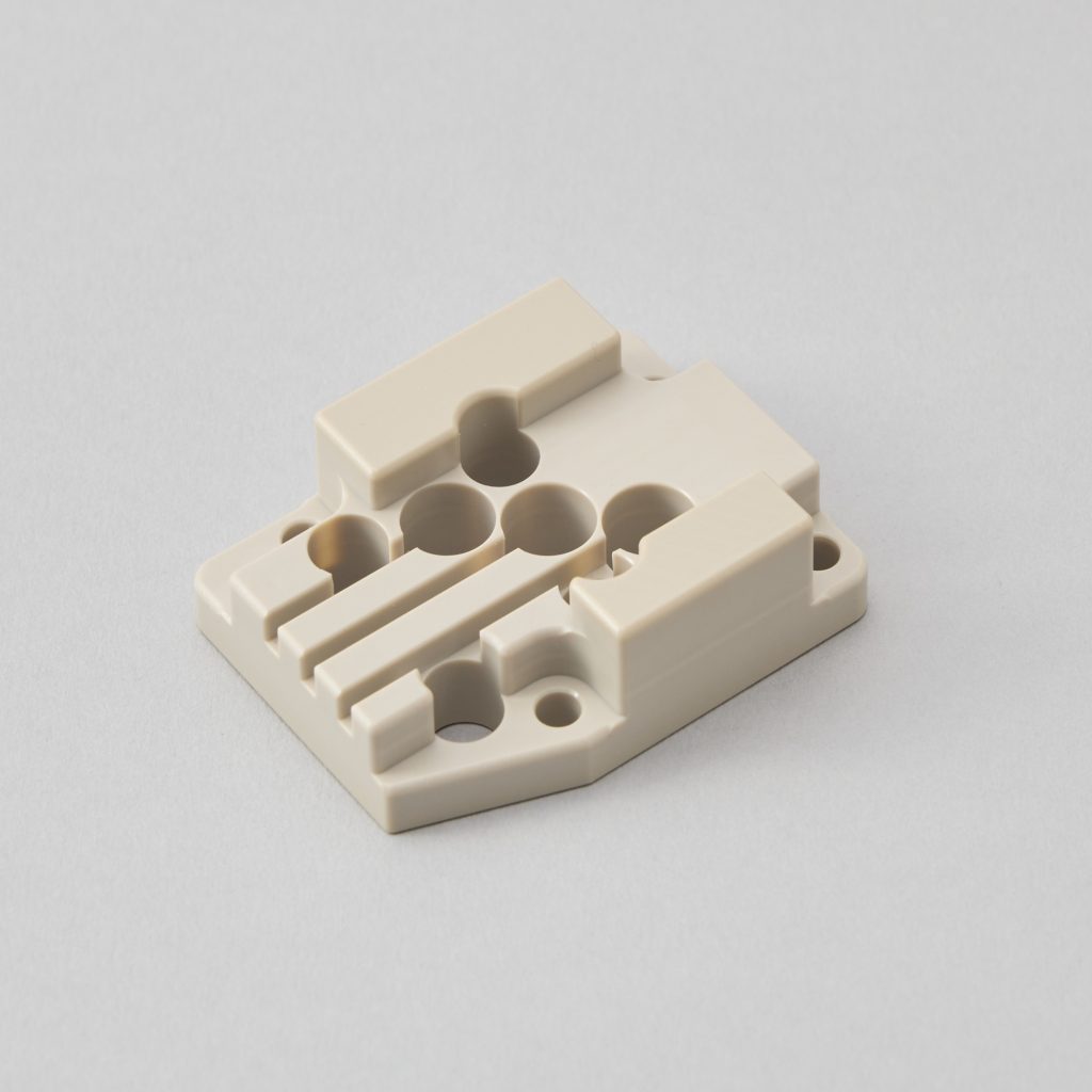 多数の微細な穴と溝加工が施された複雑形状のベージュ色樹脂パーツ